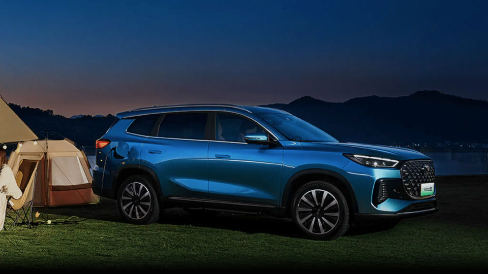 Family camping beside a lake having a meal with Chery Tiggo 8 to the right