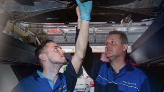 Citroën servicing, two mechanics looking under the car.