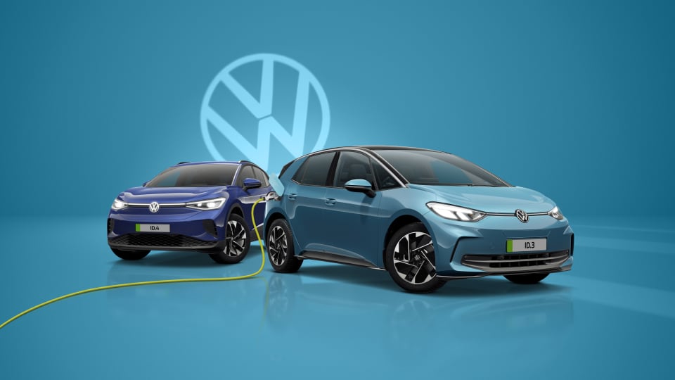 Front angled view of multiple Volkswagen vehicles with Volkswagen logo in background